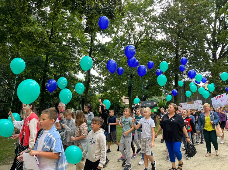 Na zdjęciu uczestnicy marszu profilaktycznego, którzy trzymają w rękach balony oraz hasła profilaktyczne