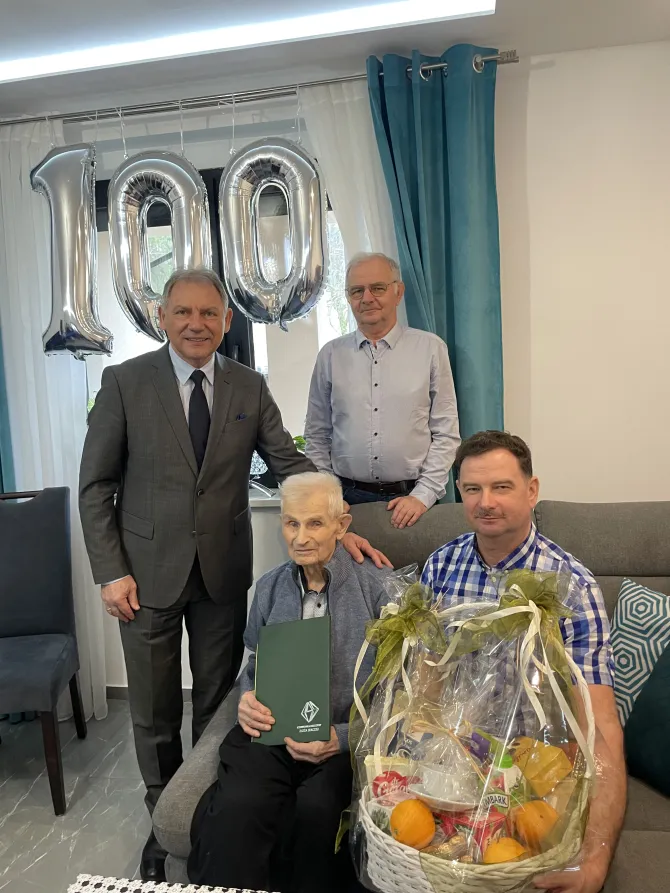 Na zdjęciu jubilat, Ryszard Szymura, wraz z synami (jeden z nich trzyma kosz pełen słodkości) oraz Burmistrzem Gminy i Miasta Czerwionka-Leszczyny Wiesławem Janiszewskim