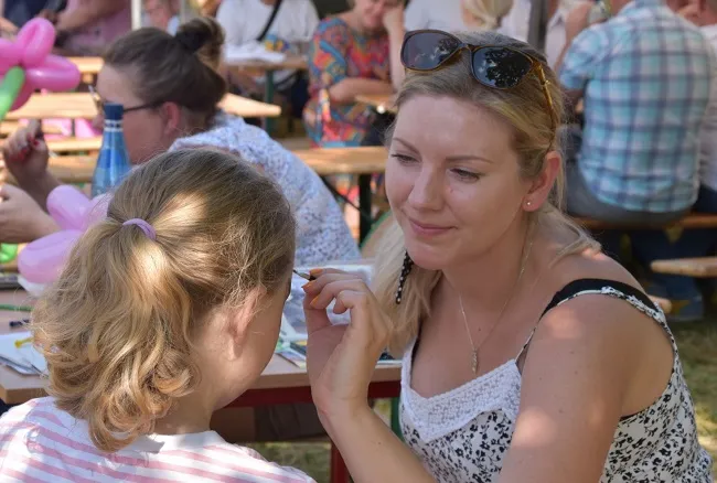 Animator malujący twarz uczestniczce festynu (zdj. Katarzyna Mazur)