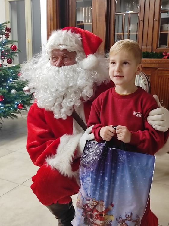 Na zdjęciu chłopczyk wraz z Mikołajem. Chłopiec trzyma w rękach paczkę z prezentami