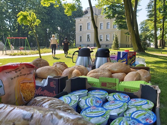 Zdjęcie przedstawiające produkty do spożycia podczas wydarzenia "Śniadanie na trawie". W tle "Zameczek" w Leszczynach.