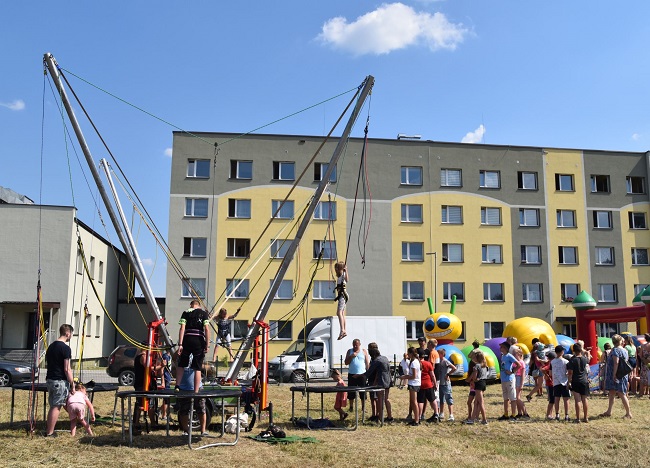 Na zdjęciu dzieci korzystające z eurobungee, czyli z trampoliny z linami, oraz pozostałe dzieci czekające w kolejce. W tle dmuchańce oraz budynek przy ulicy Młyńskiej 21A w Czerwionce-Leszczynach (zdj. Katarzyna Mazur)