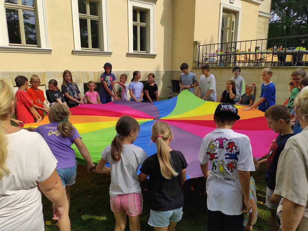 Na zdjęciu dzieci podczas zabawy z chustą animacyjną Klanza przy leszczyńskim Zameczku